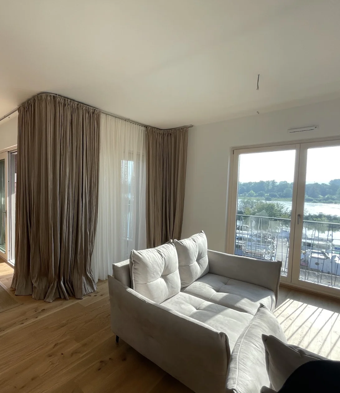 Bodenlange beige Gardinen und transparente Vorhänge an einer Fensterecke im Wohnraum