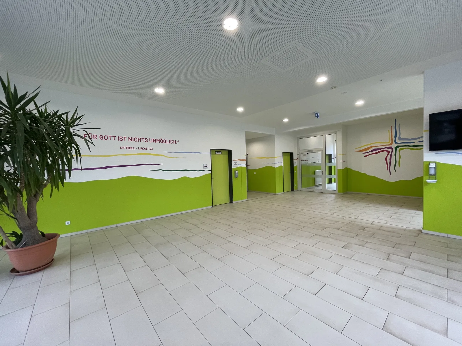 Saal mit grüner Wandgestaltung und Schriftzug