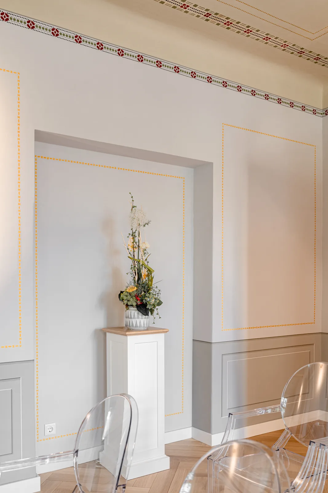 Salon mit Stuckdecke und transparenten Stühlen